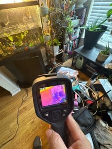 Infrared camera showing thermal readings during an on-site water-damage inspection.